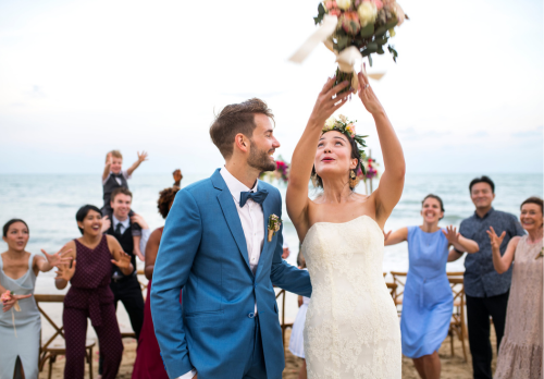 boda en la playa temática con novios tirando un ramo a los invitados